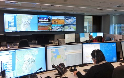 Inside Jemena's control room, showing people working at desks and looking at large computer display screens