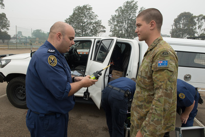 An SES volunteer hands over radios to an Army soldier