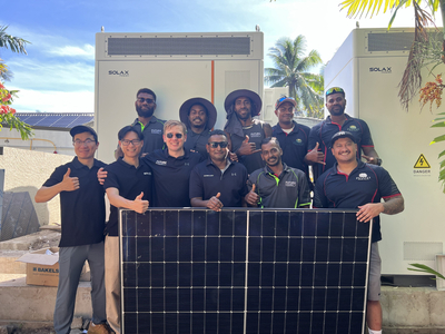 Fijian Future Energy and SolaX solar technicians with solar panel in front of batteries
